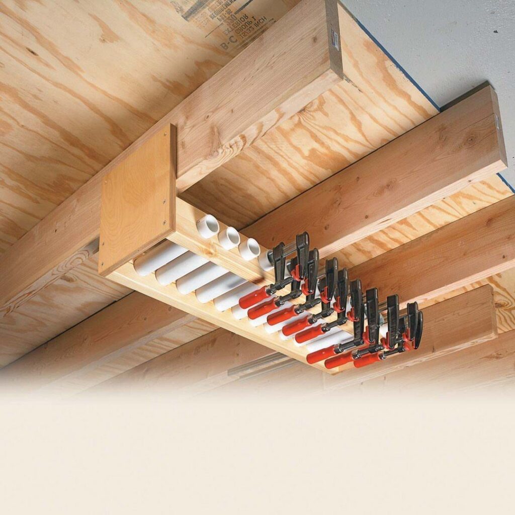 Wooden rack with PVC pipes holding red and black clamps under ceiling joists