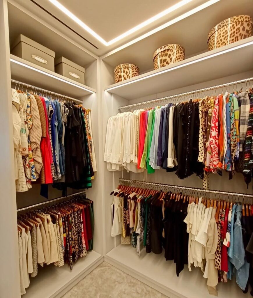 Walk-in closet with colorful clothes organized on hanging rods and leopard-print storage boxes.