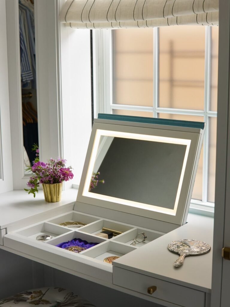 White vanity desk with flip-top mirror revealing hidden jewelry storage compartments.