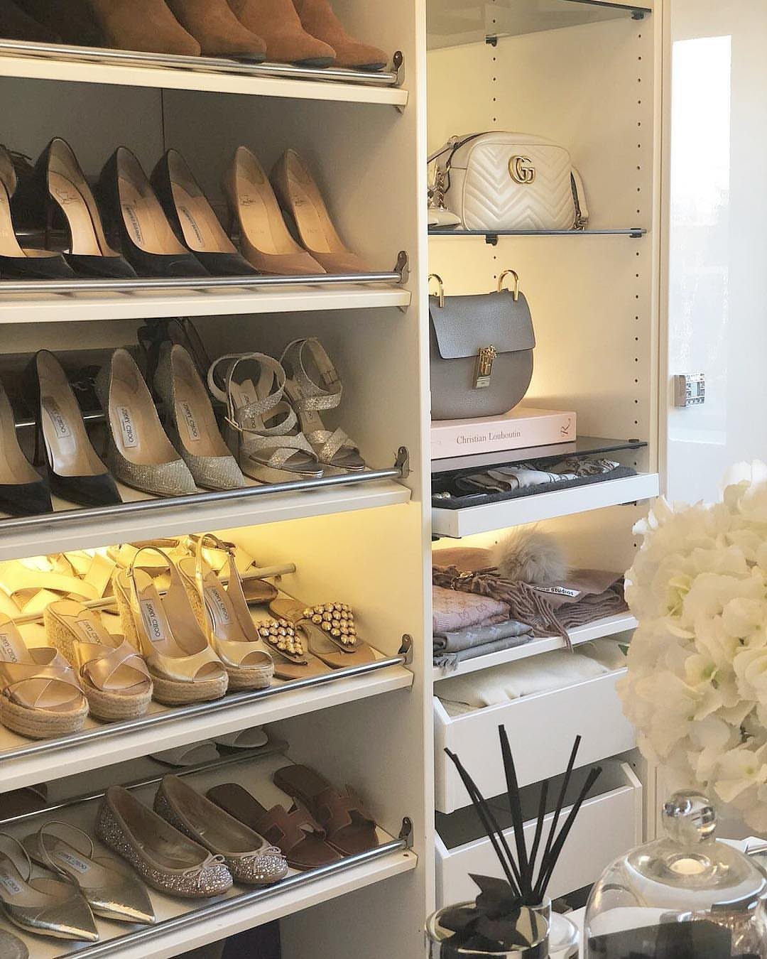 Organized white closet shelves featuring various high-heeled shoes and designer handbags.