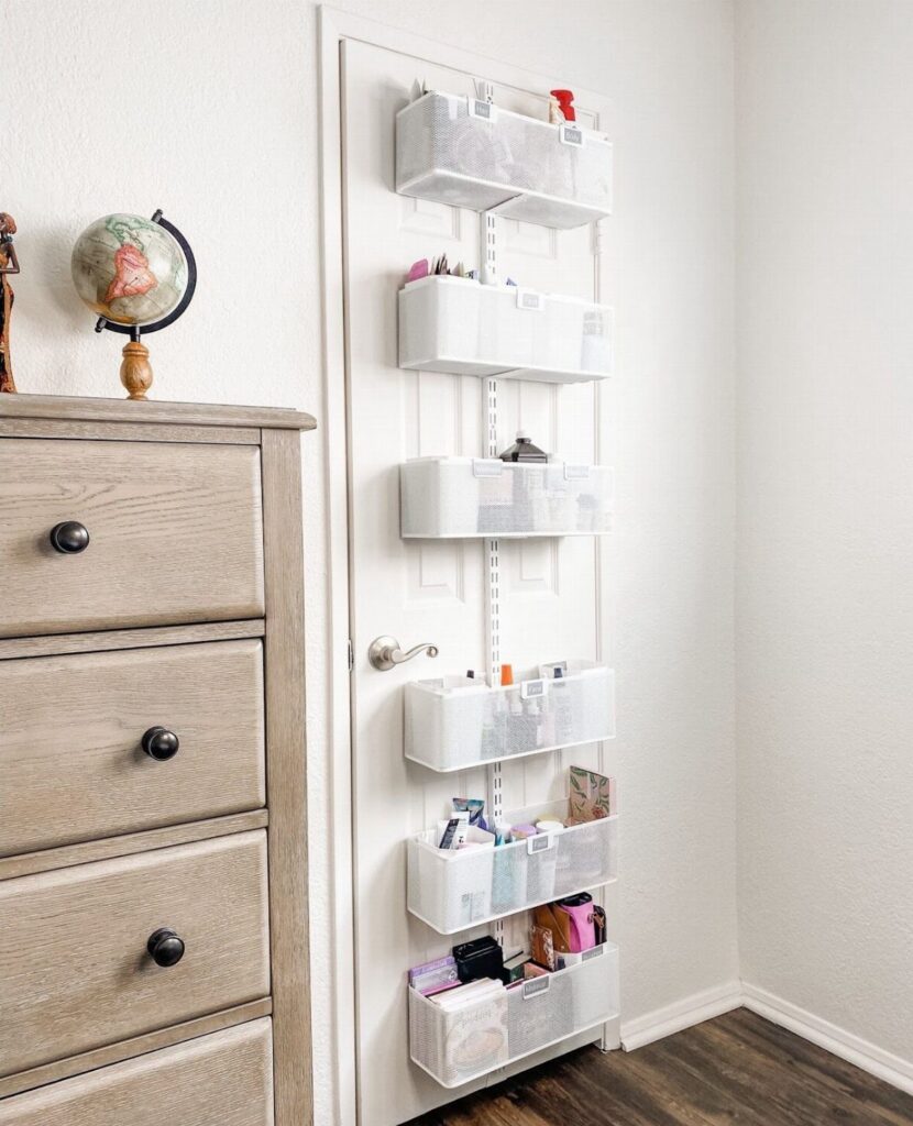 White over-the-door organizer with mesh bins for storage next to a grey dresser.