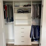 White reach-in closet with double-hang rods on the right and central shelving drawers.